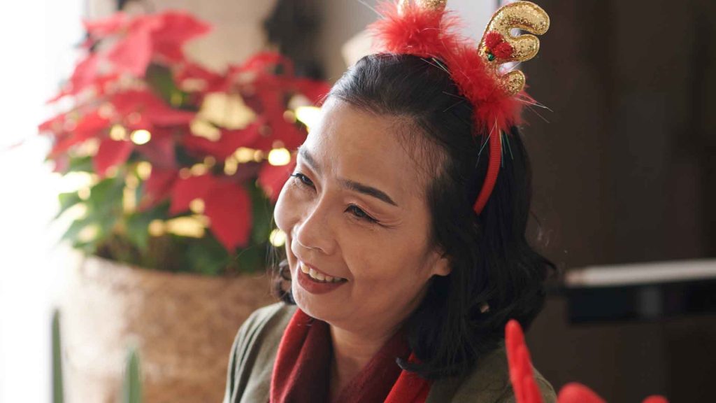 Senior smiling with holiday decor.
