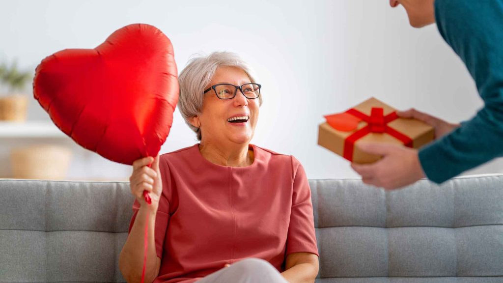 Elderly woman holding a balloon shaped as a heart.