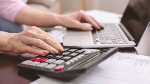 Woman with calculator and laptop.