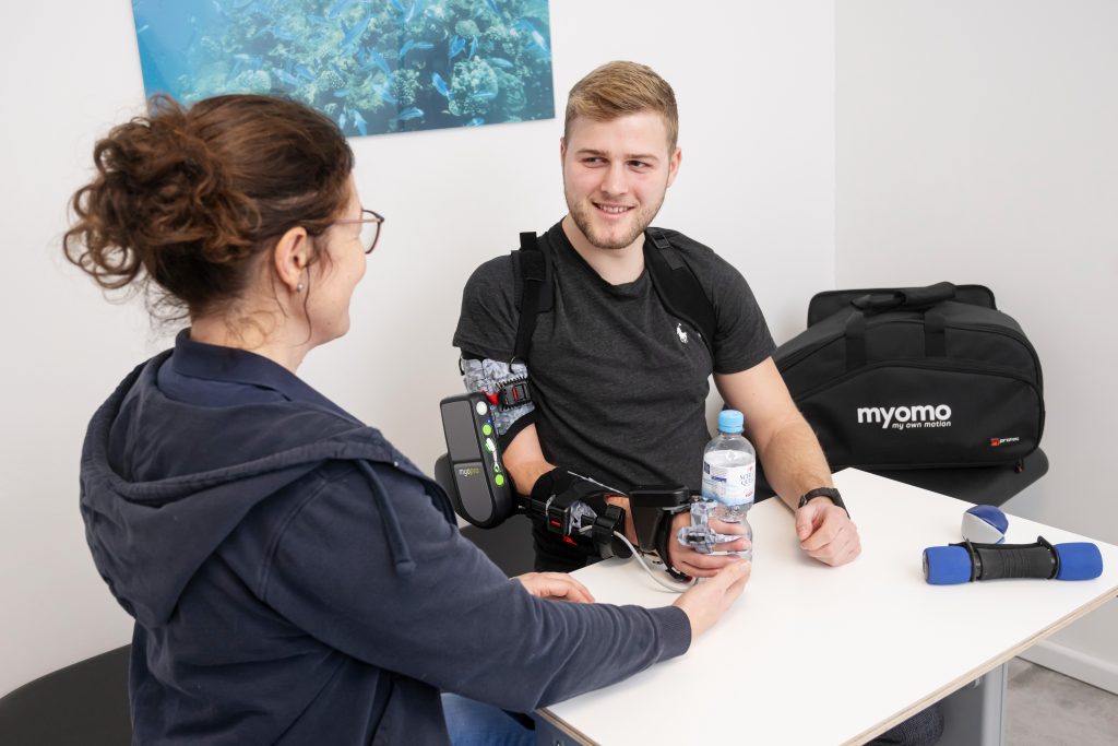 Image of MyoPro user holding a water bottle and clinician.