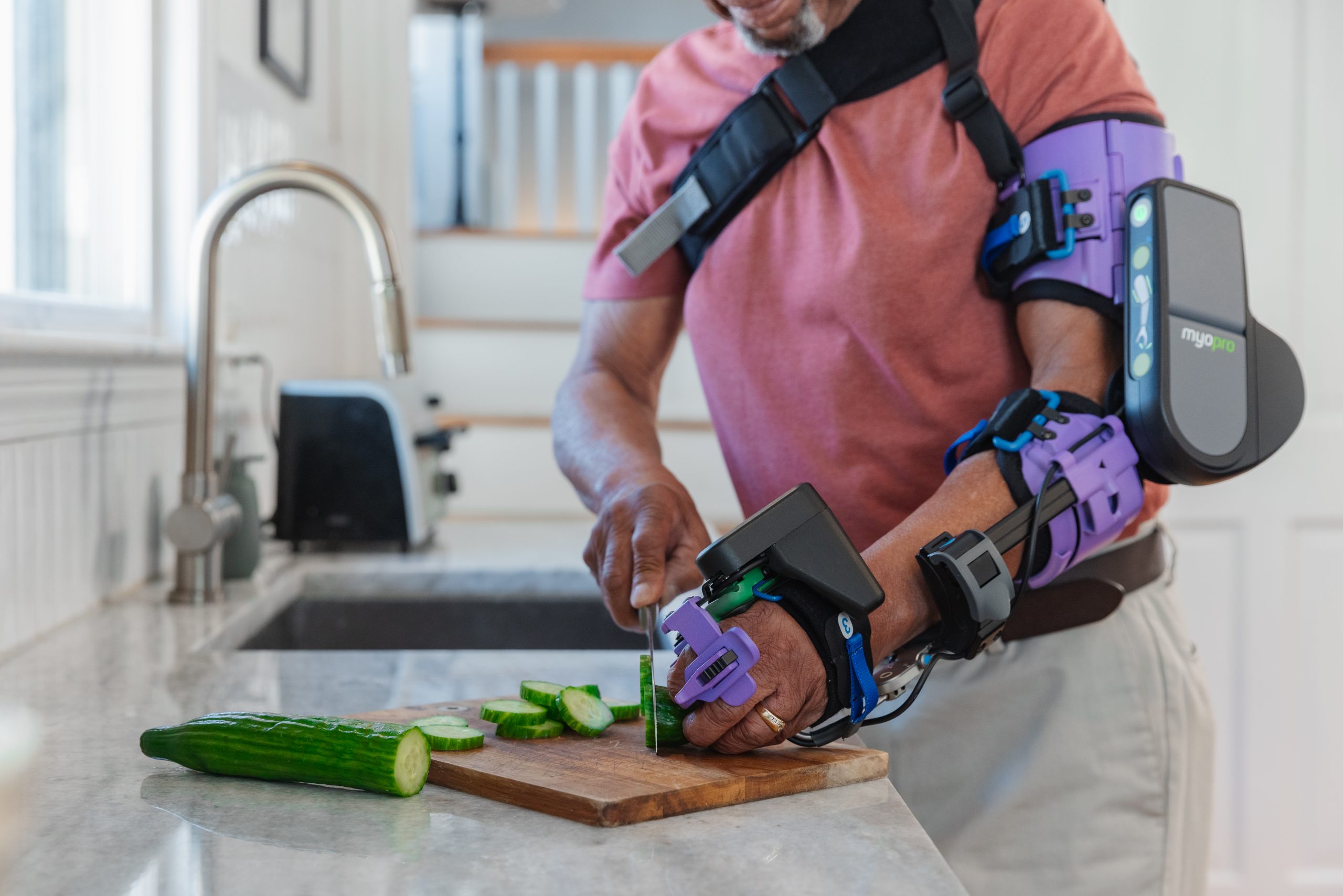 Man using a MyoPro powered arm orthosis while preparing food
